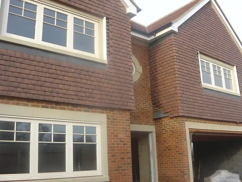 A brick house with white windows and a car parked in front of it.